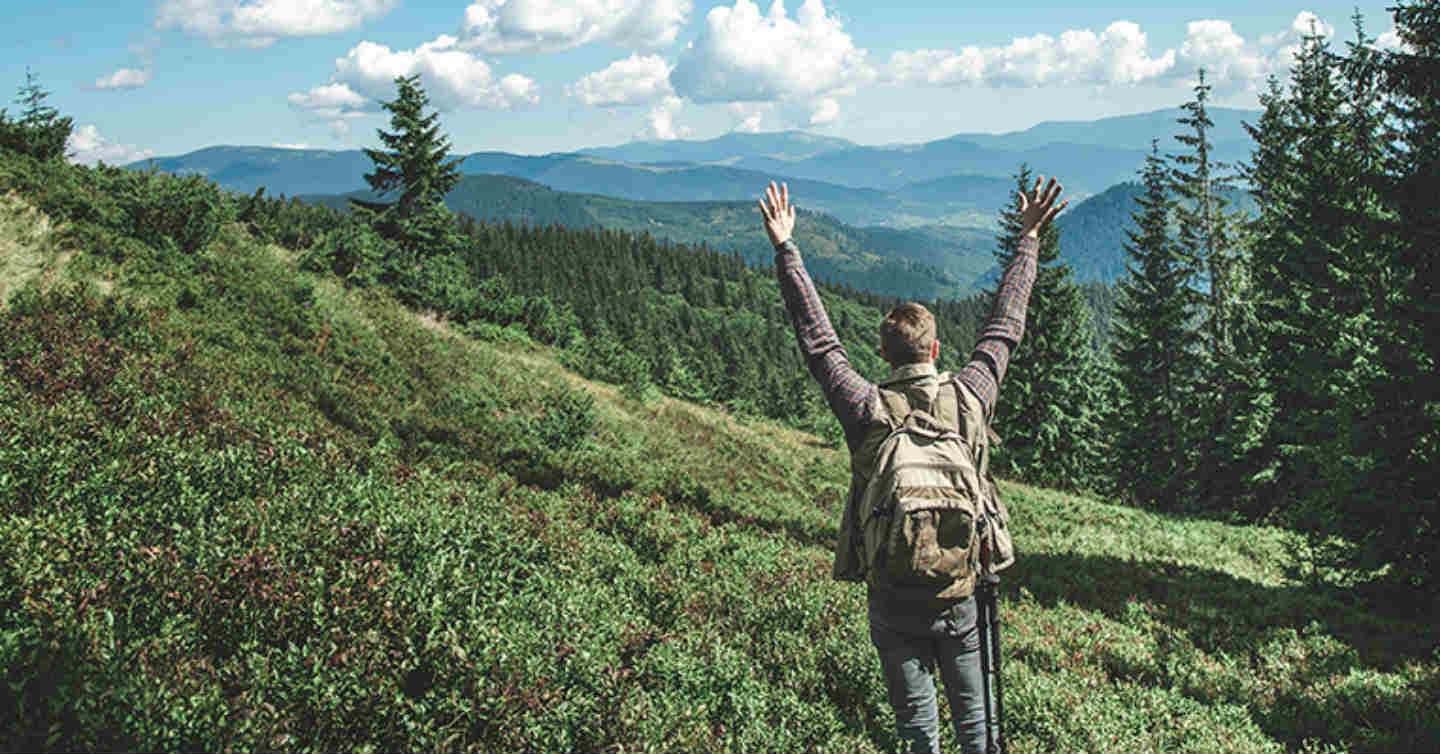 man on mountain having accomplished a SMART goal