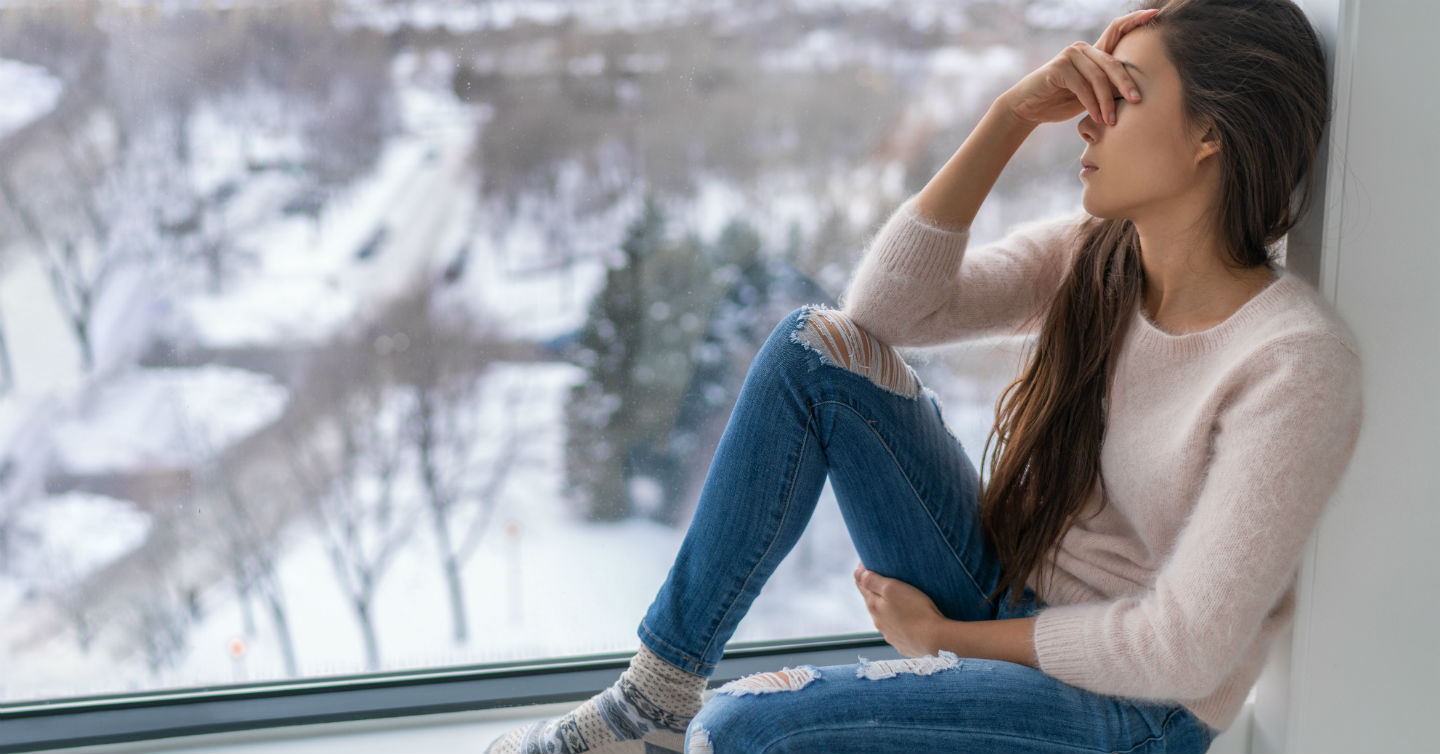 forlorn woman glancing out her large window